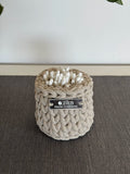 Small beige crochet storage basket used as an aesthetic makeup brush and vanity organizer on a bathroom countertop.