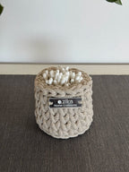 Small beige crochet storage basket used as an aesthetic makeup brush and vanity organizer on a bathroom countertop.