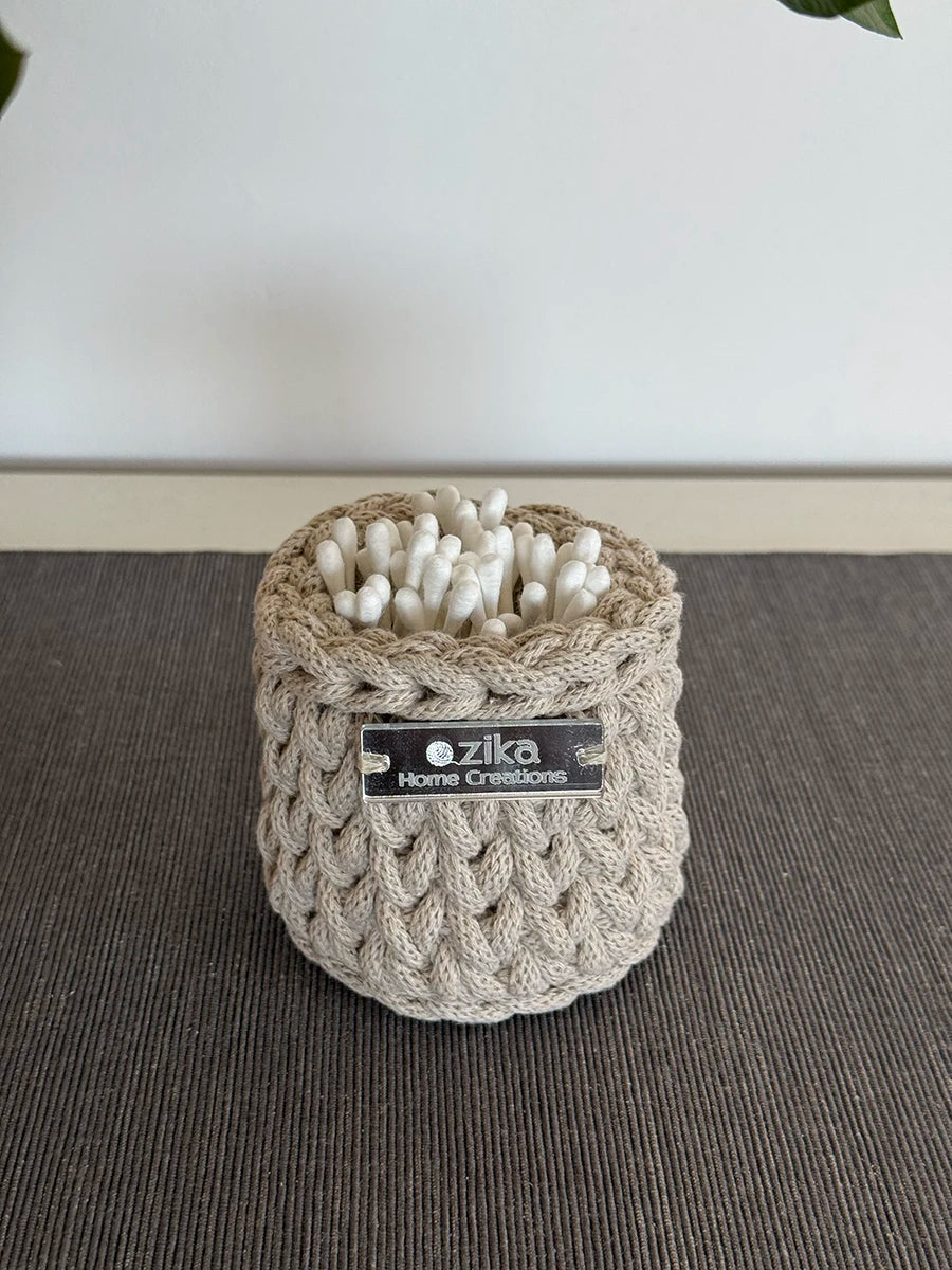 Small beige crochet storage basket used as an aesthetic makeup brush and vanity organizer on a bathroom countertop.